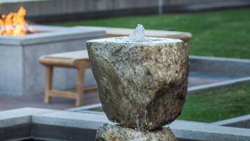 A stone fountain with water spouting from the top, surrounded by a pool.