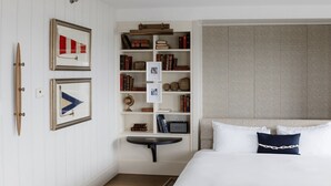 A bedroom with a bed, a bedside table, a bookshelf, and framed pictures on the wall. - The Harborvale, Autograph Collection (Burlington)