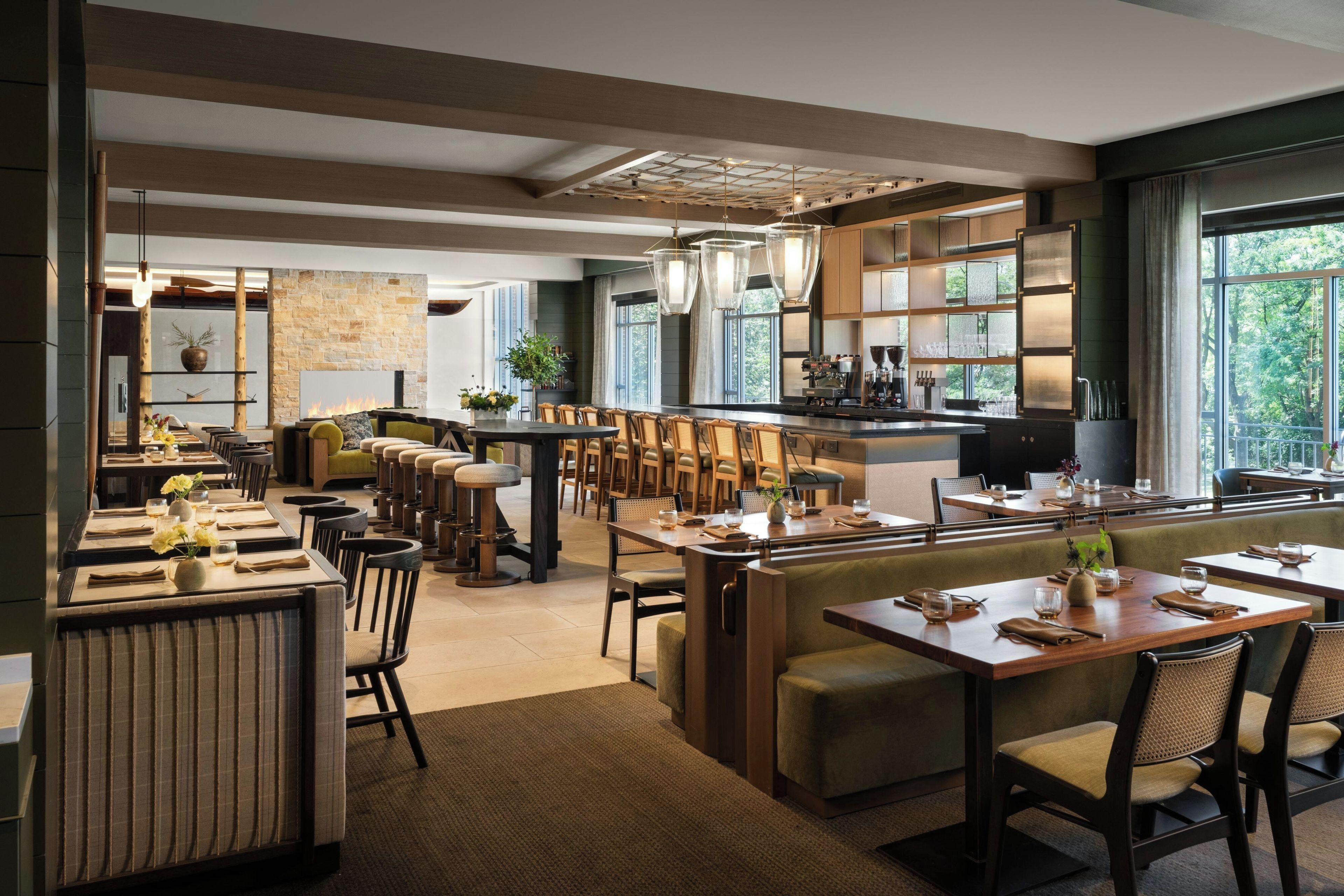 A modern restaurant with high ceilings, exposed beams, and a mix of seating arrangements including booths and tables.