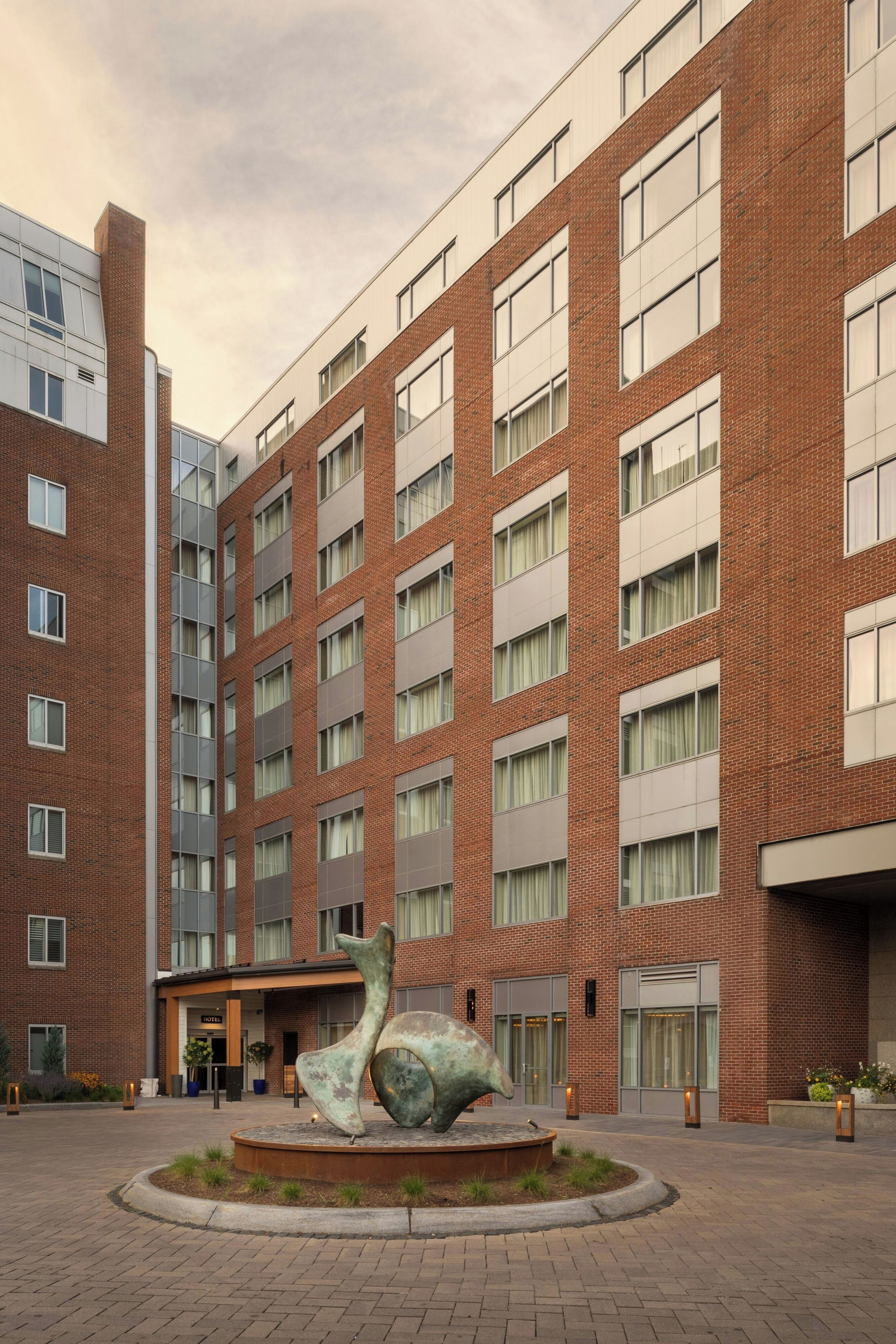 A multi-story hotel with a central courtyard featuring a sculpture.