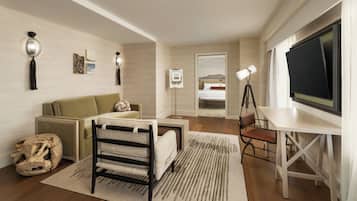 Un salon moderne comprenant un canapé, un fauteuil, une table basse, un téléviseur et un bureau avec une lampe.