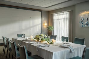 Zona pranzo con un lungo tavolo apparecchiato per un pasto, circondato da sedie e decorato con candele e fiori.