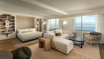 Una habitación de hotel moderna con cama, sofá, sillón y vista al mar.