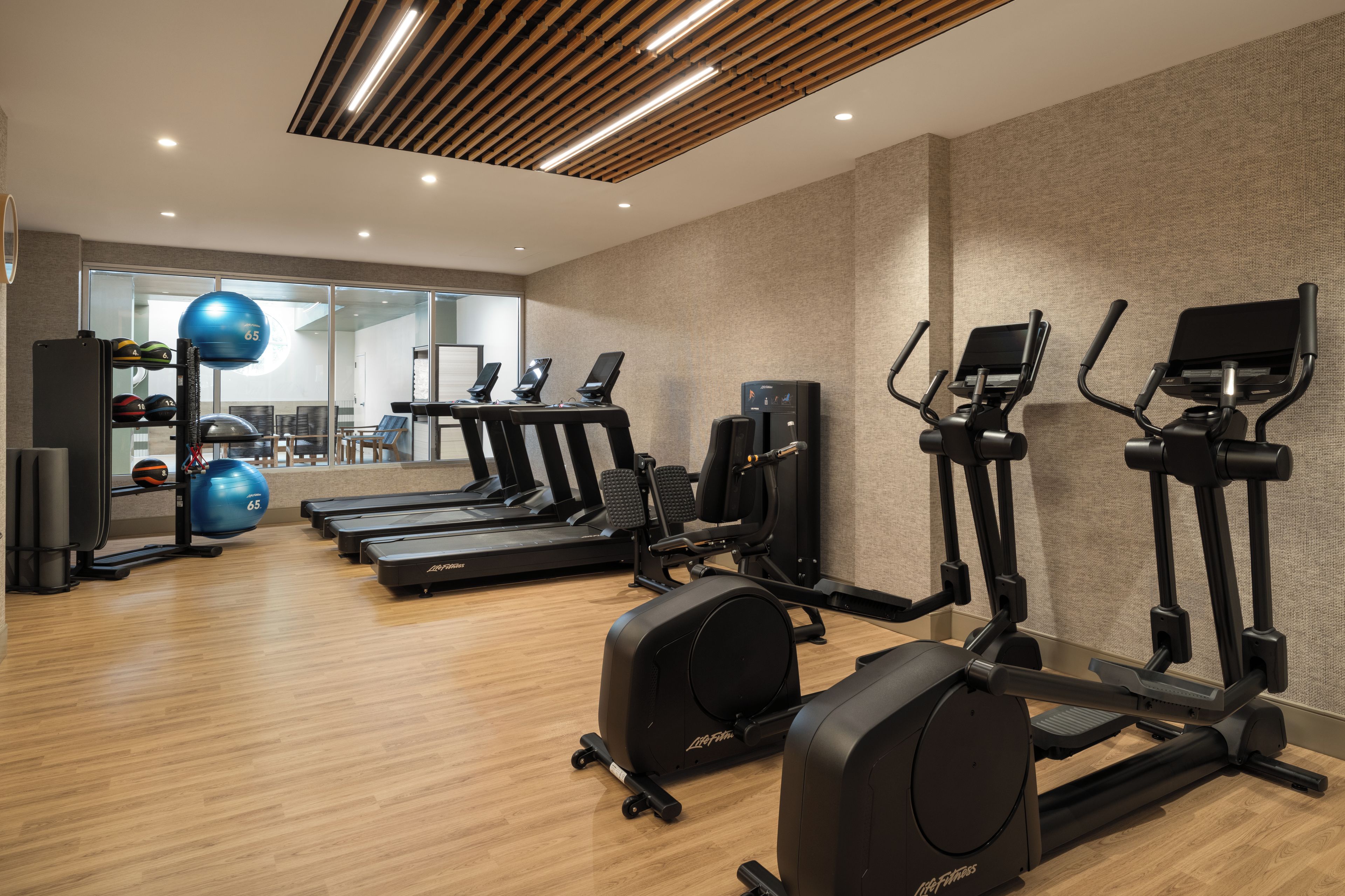 A gym with treadmills, elliptical machines, and exercise balls.