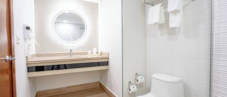 Un baño moderno con un espejo redondo, un lavamanos, un inodoro y una cabina de ducha de vidrio.