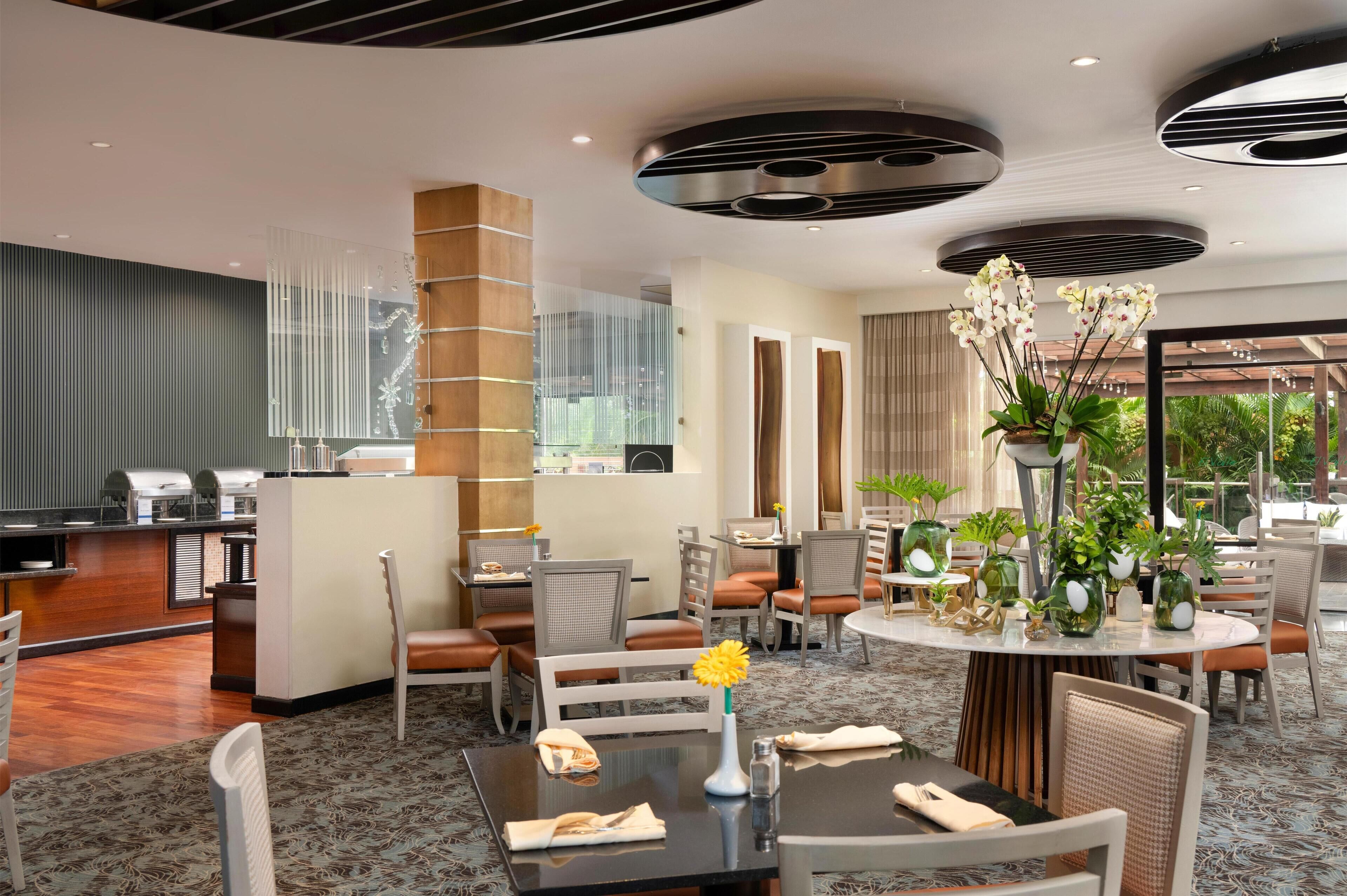 A modern hotel lobby with a reception desk, seating area, and large windows offering a view of the outdoors.
