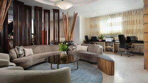 A modern living room with a sectional sofa, a round coffee table, and a desk area with two computers. - Hodelpa Garden Court (Punal)