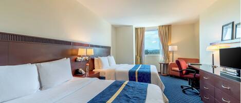 A hotel room with two beds, a desk, a chair, a TV, and a window with curtains.