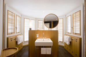 A modern bathroom with a central sink, wooden vanity, and a round mirror.