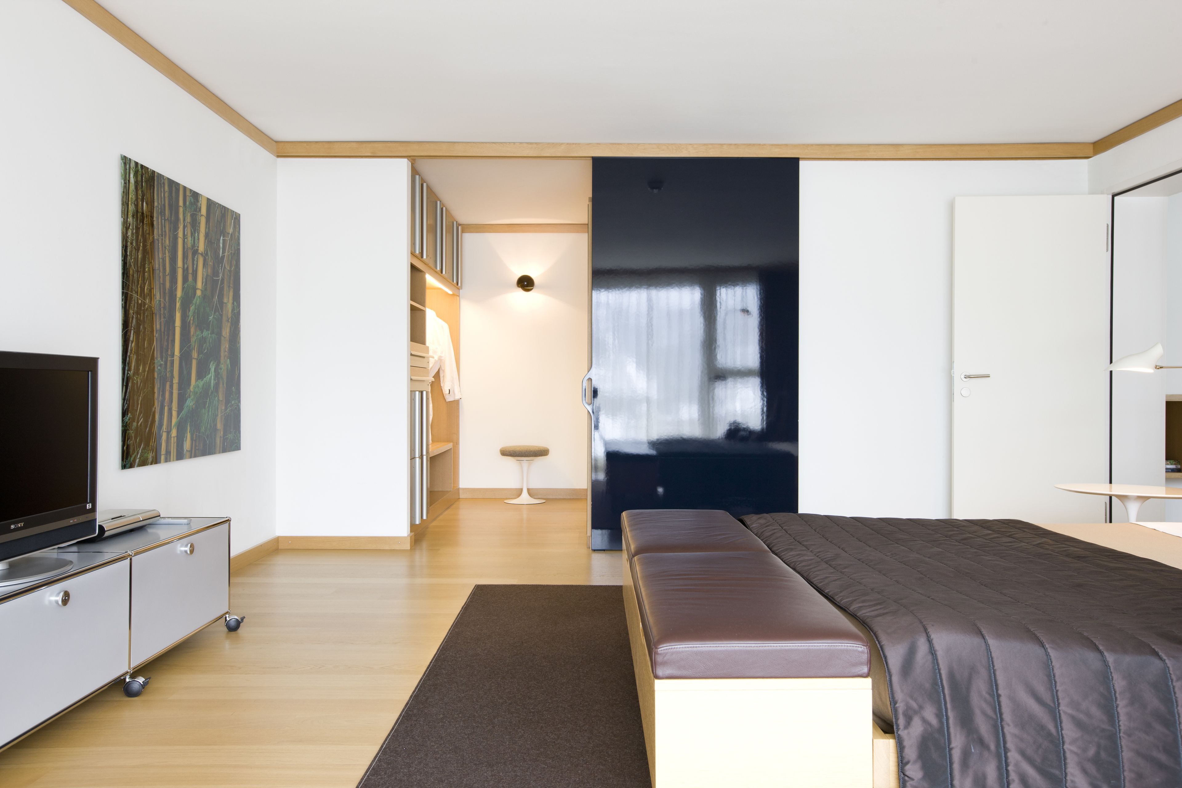 Una camera da letto moderna con un letto grande, una televisione su un mobile, una scrivania e un armadio.