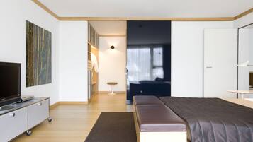 Una camera da letto moderna con un letto grande, una televisione su un mobile, una scrivania e un armadio.