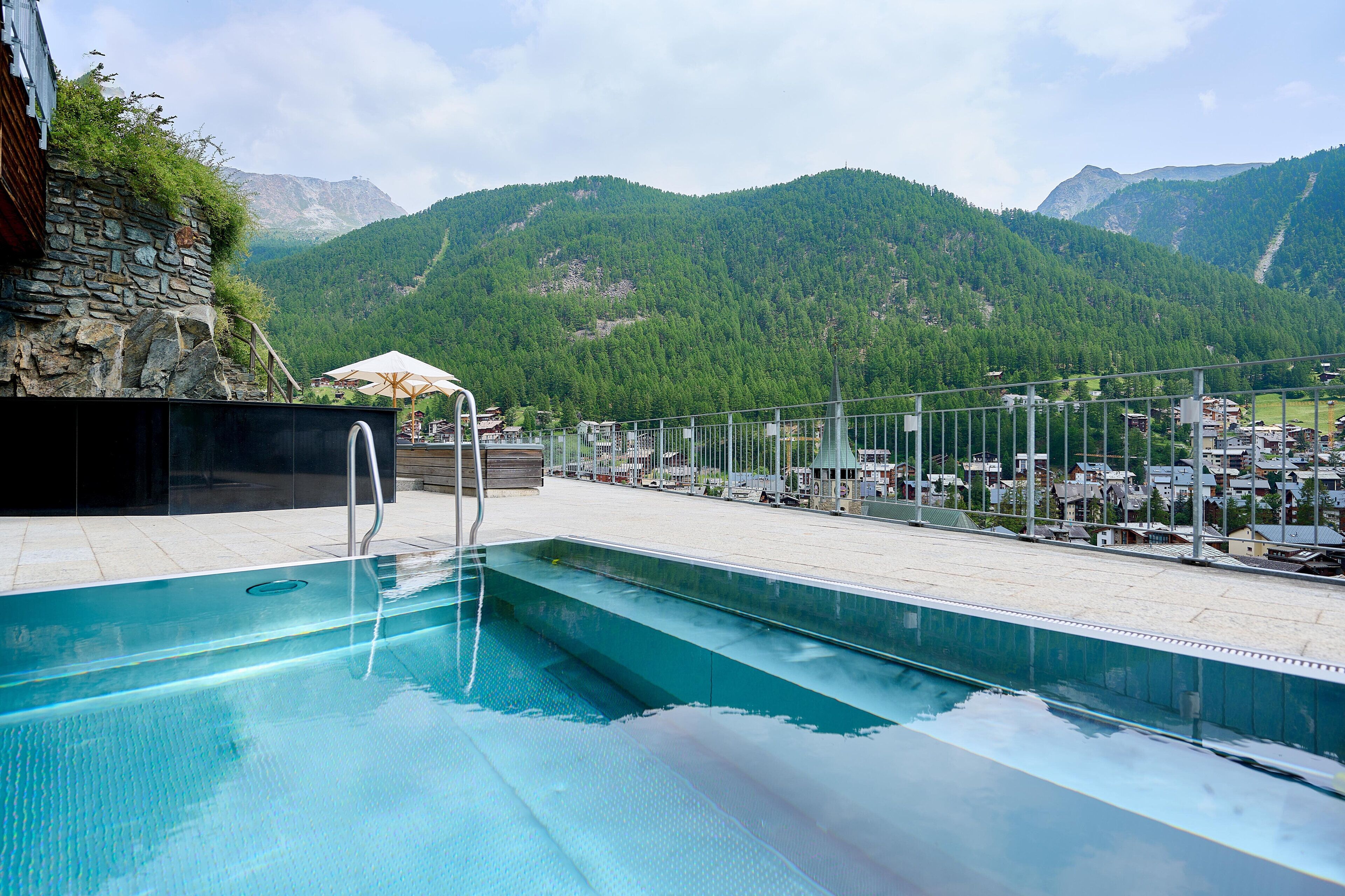 Alberca techada, alberca al aire libre y sombrillas en la alberca