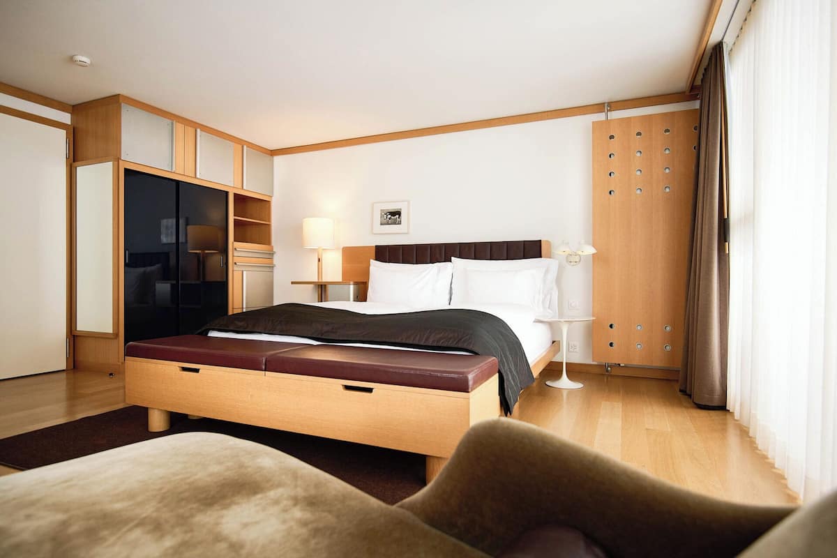 Una habitación de hotel moderna con una cama grande, un armario, un escritorio y una zona de estar.