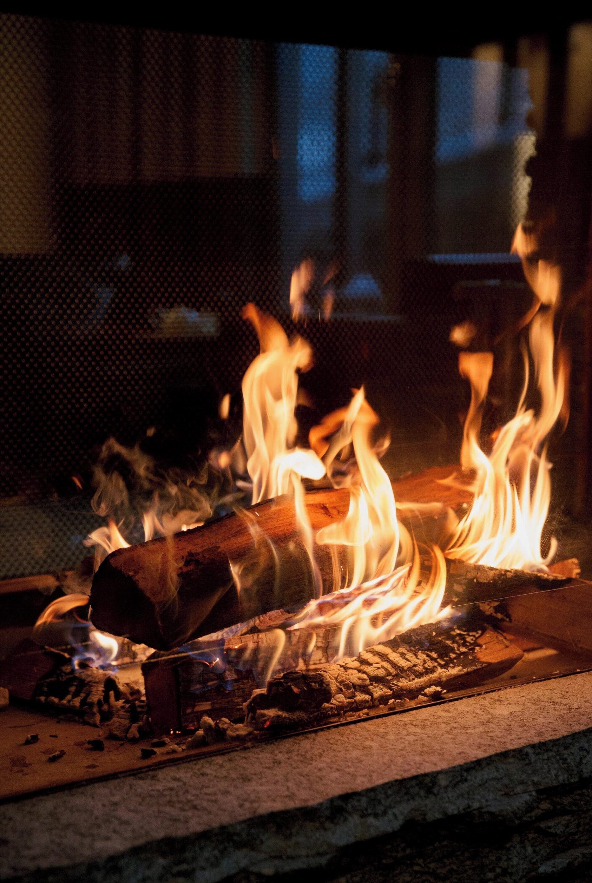 Ein Kamin mit brennenden Holzscheiten und Flammen.