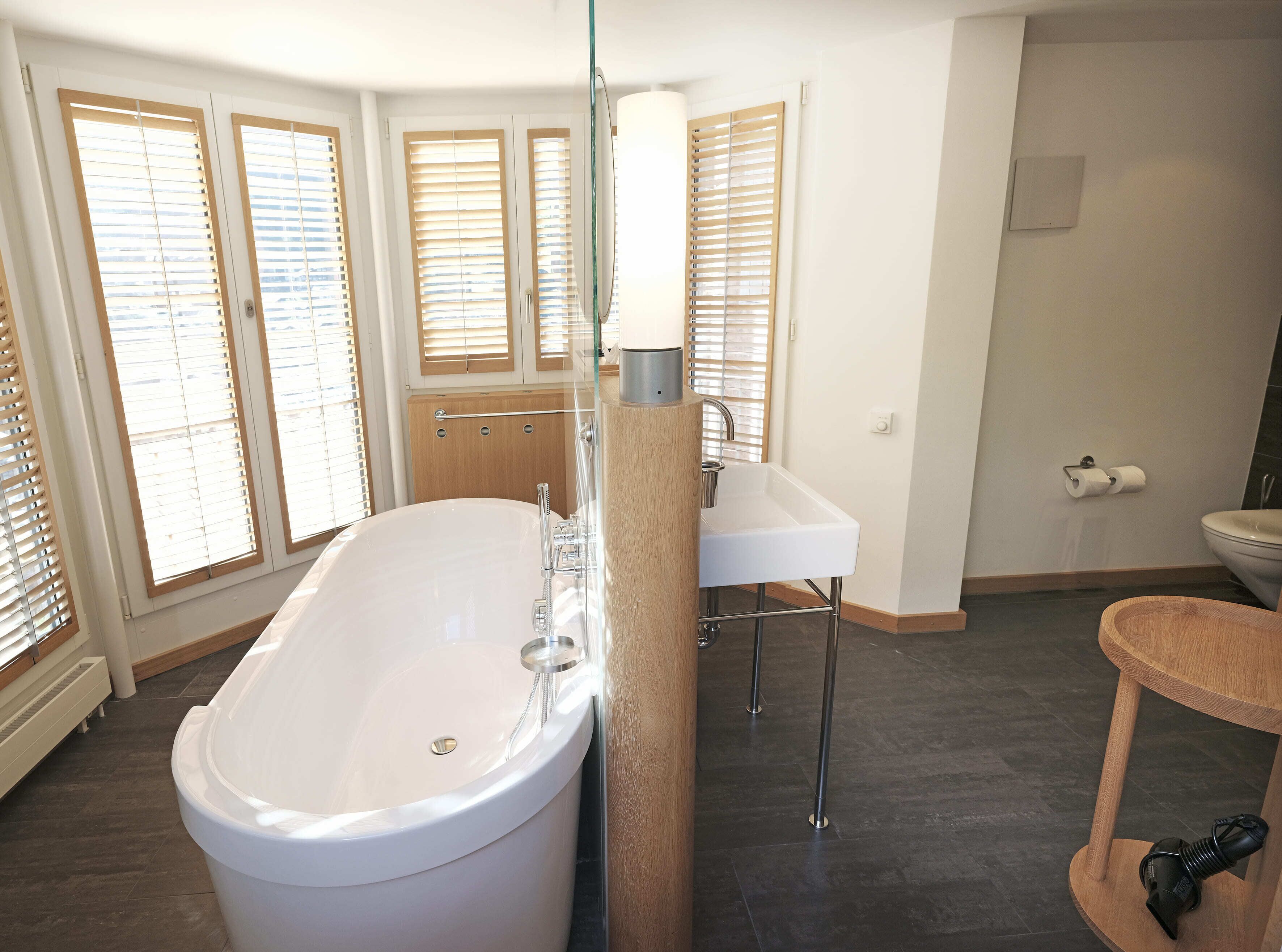 Et moderne badeværelse med et fristående badekar, en hvid vask og et toilet.