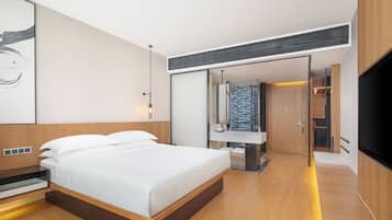 Un dormitorio moderno con una cama grande, mesitas de noche empotradas, un vestidor y un baño con un lavamanos y espejo modernos.