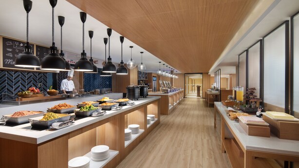 A modern kitchen with long counters, black pendant lights, and a chef in uniform. - Fairfield by Marriott Ningbo Yinzhou (Ningbo)