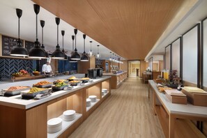 A modern kitchen with long counters, black pendant lights, and a chef in uniform. - Fairfield by Marriott Ningbo Yinzhou (Ningbo)