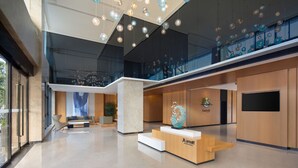 A modern hotel lobby with a reception desk, seating area, and a large glass staircase. - Fairfield by Marriott Ningbo Yinzhou (Ningbo)