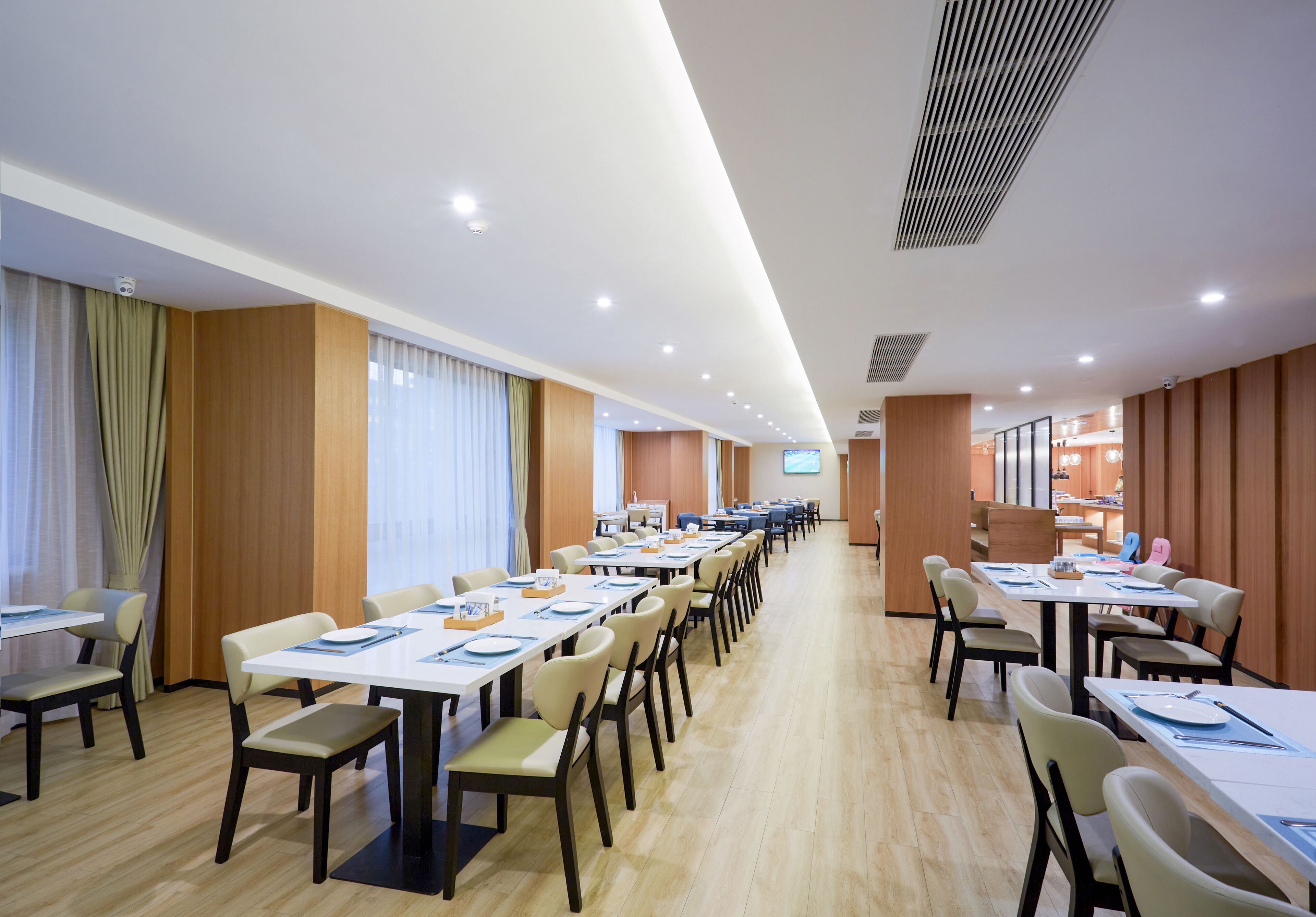 A hotel conference room with long tables, chairs, and a projection screen.