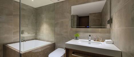 A modern bathroom with a glass-enclosed shower, a white bathtub, a toilet, and a vanity with a mirror.