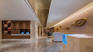 A modern hotel lobby with a marble floor, wooden reception desk, and a seating area with chairs. - Guangzhou Hotel - Canton Fair Free Shuttle Bus (Guangzhou)