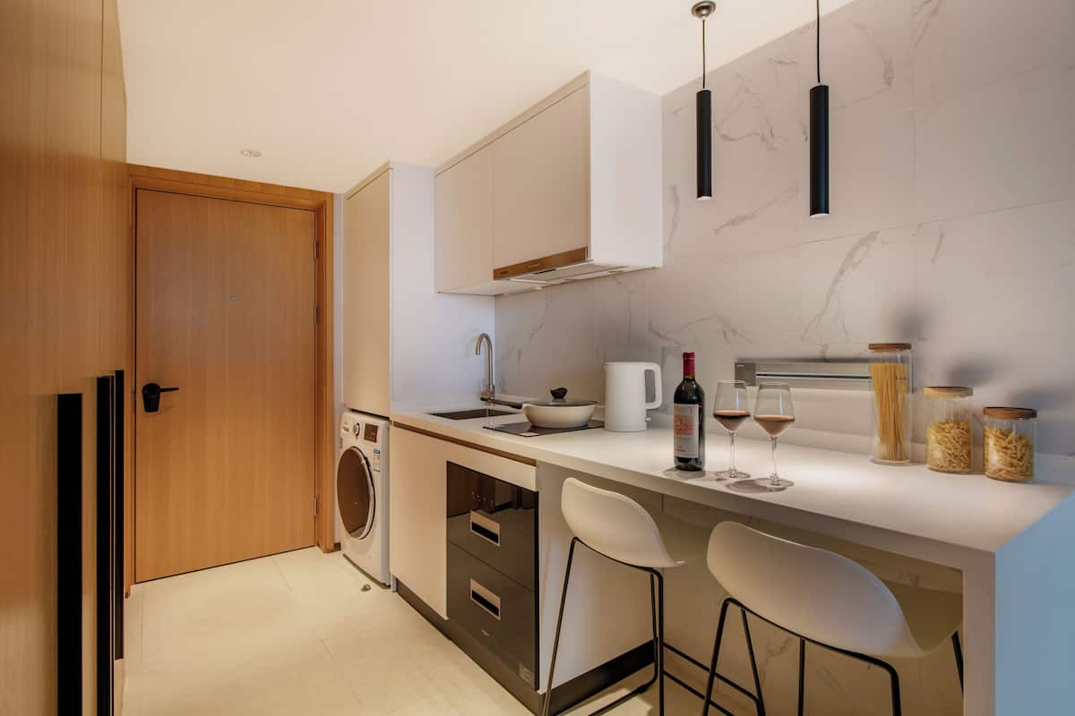 Una cocina moderna con lavadora integrada, un fregadero y una zona de bar con dos taburetes.