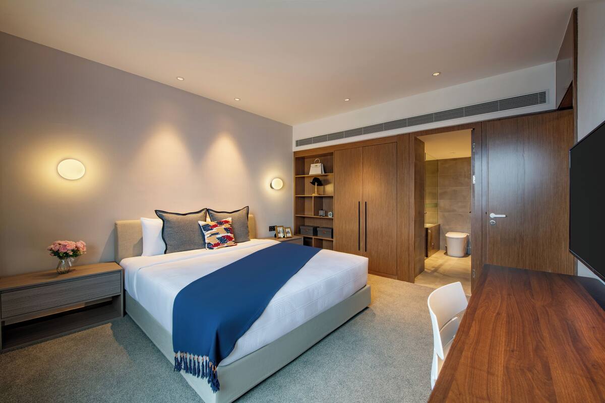 Una habitación de hotel moderna con una cama grande, mesitas de noche, un escritorio y un armario.