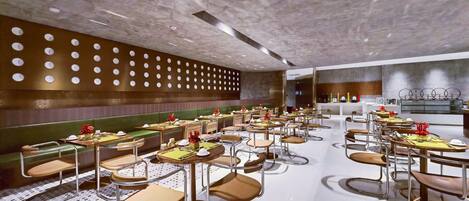 A modern restaurant with booths and tables, a patterned floor, and a ceiling with circular cutouts.