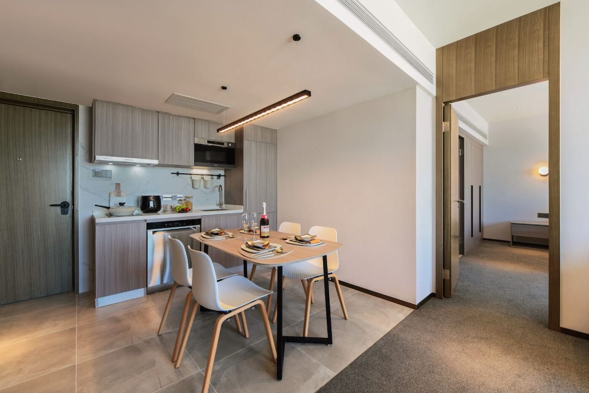 Una cocina moderna con comedor, que incluye un horno empotrado, microondas y una mesa de comedor lista para cuatro personas.