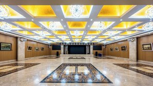 A spacious hotel lobby with a large central carpet, ceiling chandeliers, and framed artwork on the walls. - AC Embassy Hotel (Beijing)