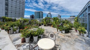 A rooftop garden with potted plants and a table, surrounded by modern buildings. - AC Embassy Hotel (Beijing)