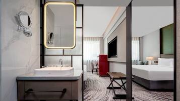Un baño de hotel moderno con un espejo grande, un lavabo y un mueble rojo.
