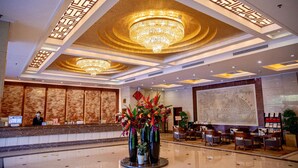 A hotel lobby with a reception desk, a large chandelier, and a seating area with chairs. - Shenzhen Liyuan Hotel (Shenzhen)