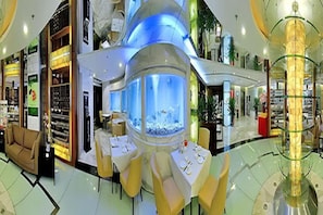 Un espacio interior amplio con un gran acuario, zonas de estar y diversas tiendas.