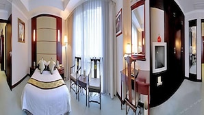 A hotel room with a large bed, a desk with a television, and a chair. - Shenzhen Liyuan Hotel (Shenzhen)