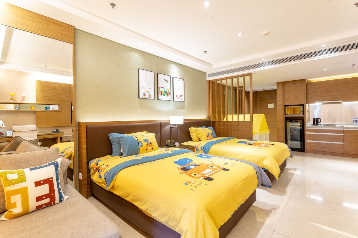Habitación de hotel con dos camas, kitchenette, baño y un espejo grande.
