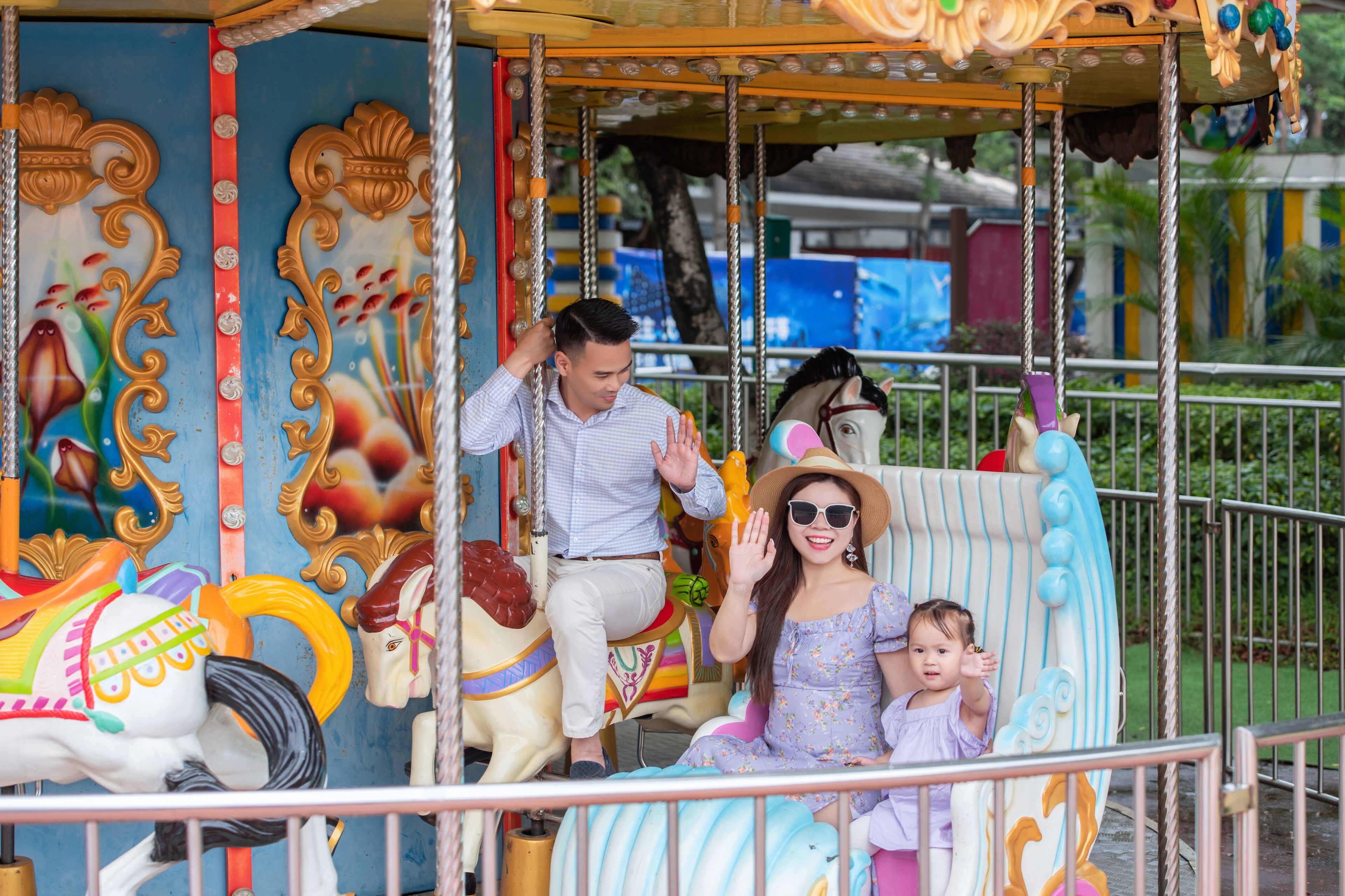 A carousel with ornate decorations and a man and a woman with a child on it.