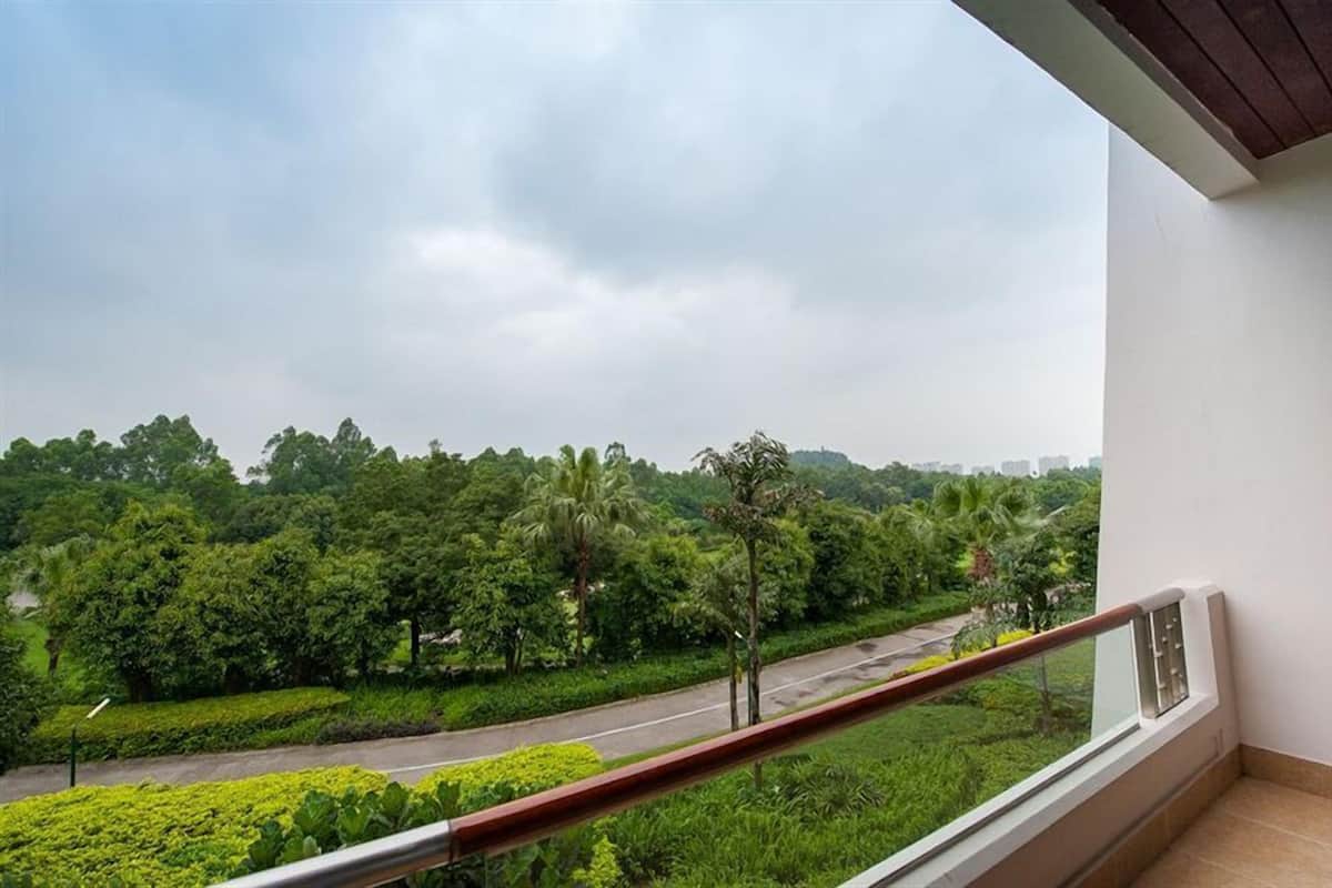 Ein Balkon mit Blick auf eine Straße und Grünflächen.