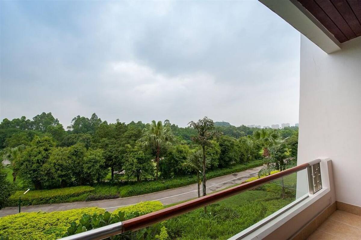 Ein Balkon mit Blick auf eine Straße und Grünflächen.