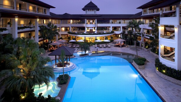 A hotel with a large central pool, multiple balconies, and outdoor seating areas. - Mission Hills Resort Shenzhen (Shenzhen)
