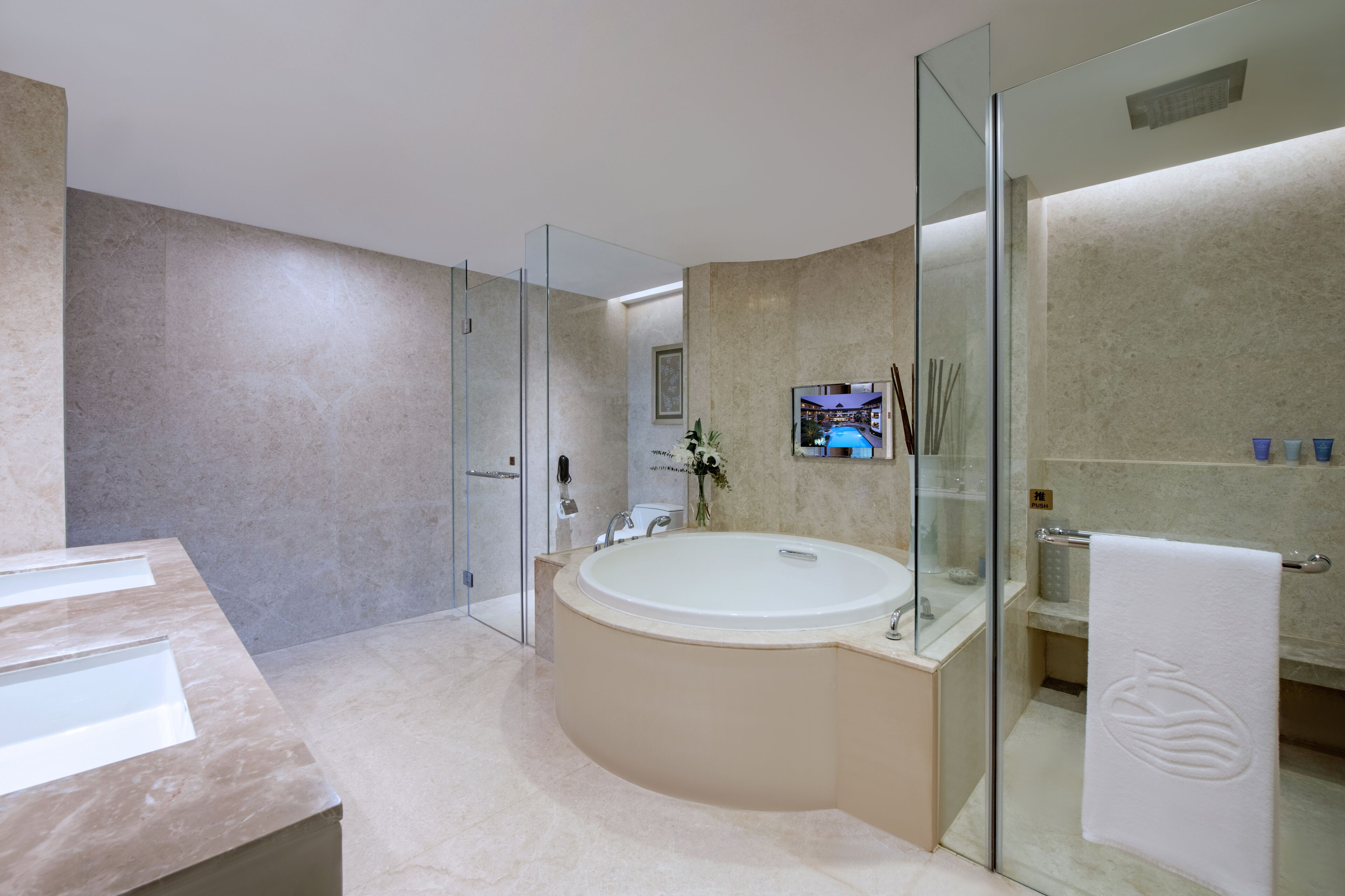 A modern bathroom with a large bathtub, a glass-enclosed shower, and a vanity with a mirror.