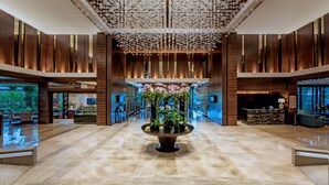 A spacious lobby with a central floral arrangement, wooden paneling, and a reception desk. - Mission Hills Resort Shenzhen (Shenzhen)