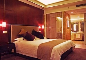 A hotel room with a large bed, a nightstand, and a mirror. - Jade Emperor Hotel (Hangzhou)