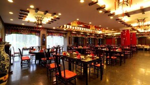 L’intérieur d’un restaurant chinois traditionnel, avec de nombreuses tables et chaises, des décorations raffinées et un grand vase placé à gauche.