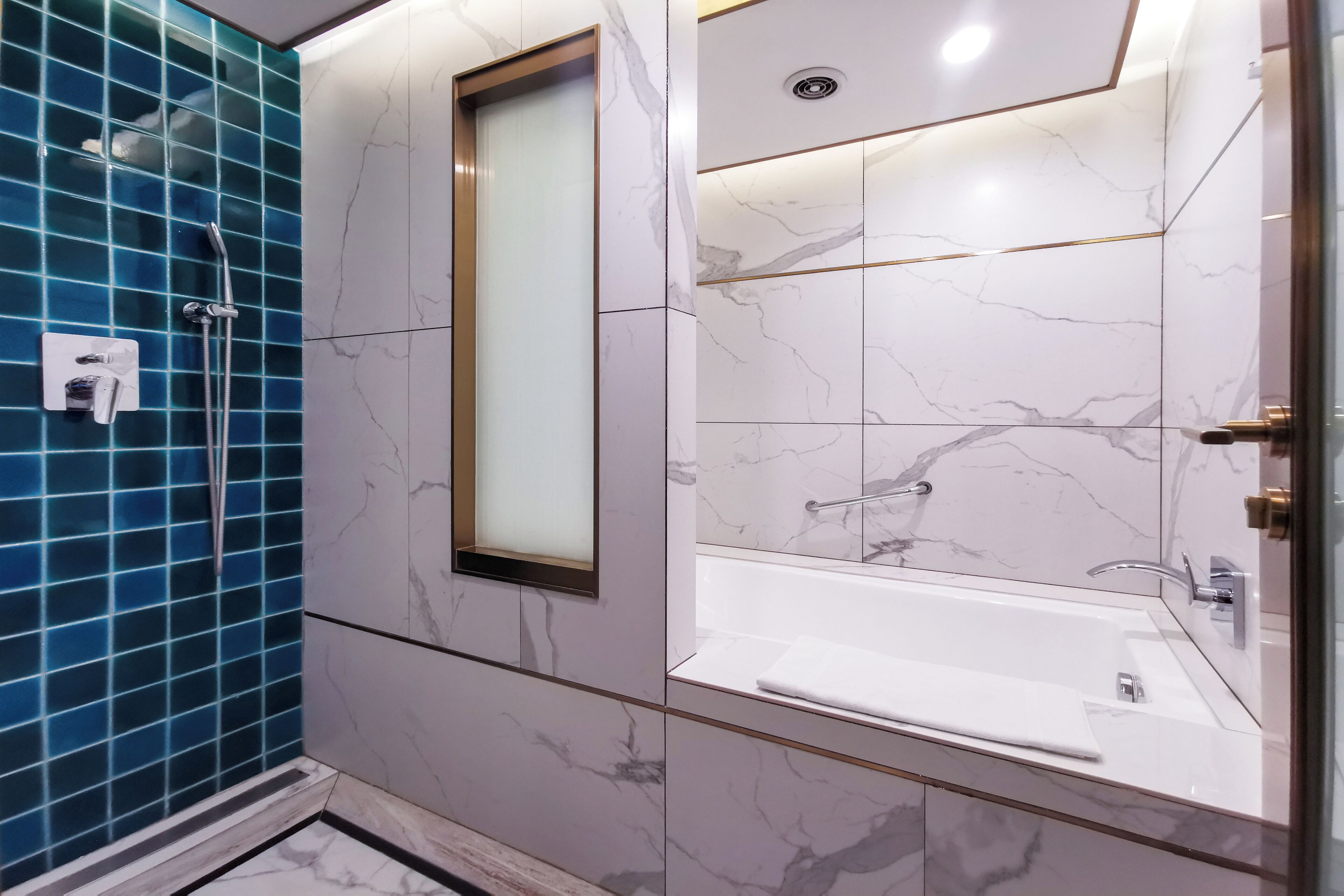 Une salle de bain moderne dotée d’une douche à parois de verre, d’une grande baignoire et de carreaux de marbre.