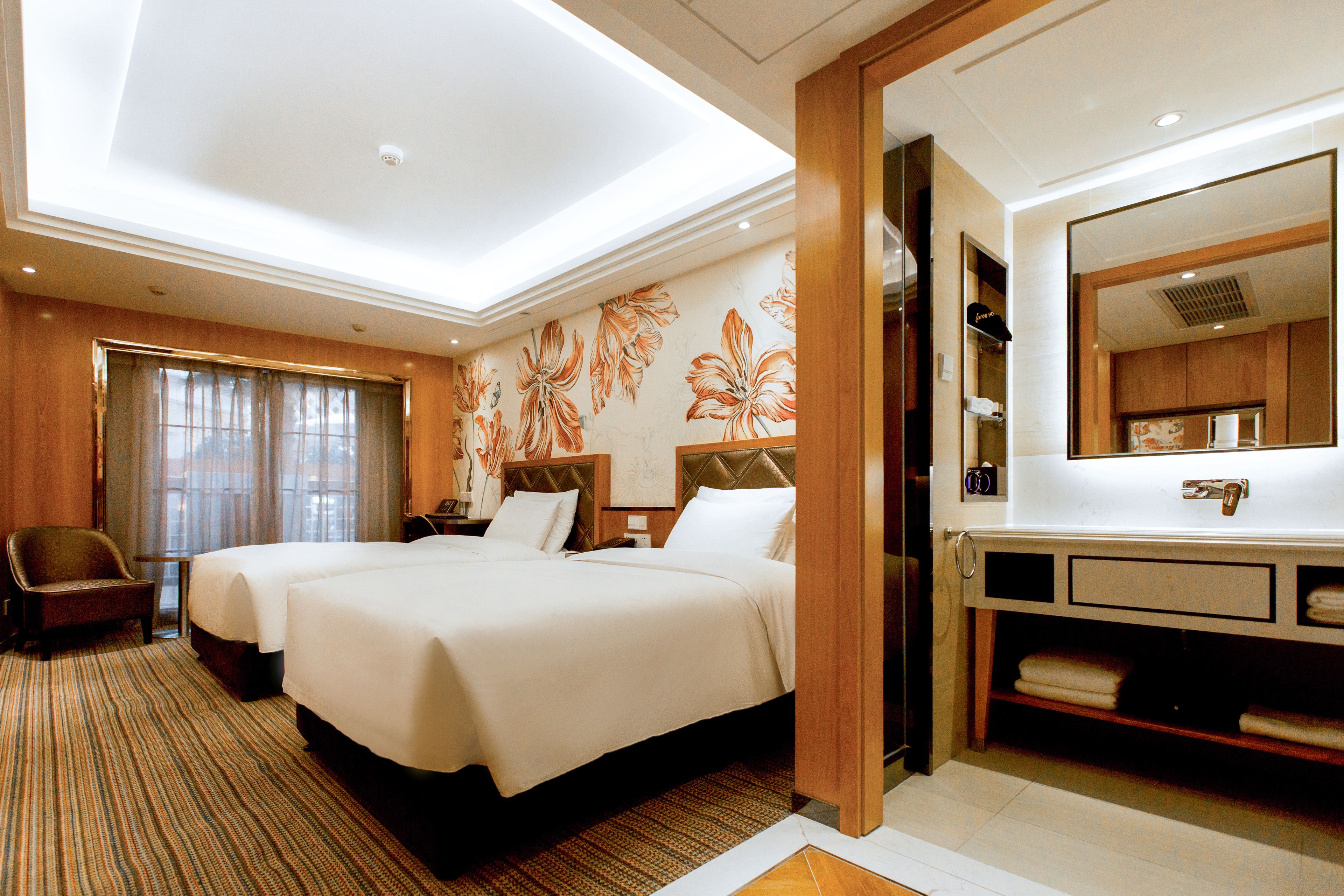 A hotel room with two beds, a large mirror, a wooden vanity, and a window with curtains.