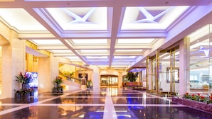A spacious lobby with a high ceiling, reflective floor, and symmetrical design. - Nanjing Central Hotel (Nanjing)