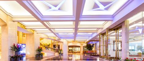 A spacious lobby with a high ceiling, reflective floor, and symmetrical design.