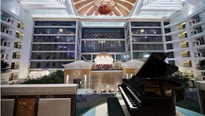 A grand atrium with a central chandelier, a grand piano, and a reflective water feature. - Nanjing Central Hotel (Nanjing)